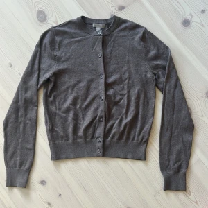 Brun kofta från H&M i bomull, S - Säljer en enkel brun kofta från H&M i storlek S. Koftan har rund halsringning, långa ärmar och knäppning framtill med matchande knappar. Bra skick. Säljer då jag den inte kommer till användning💕