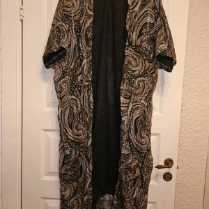 Mönstrad Cardian/kimono från Lindex - Säljer en Cardian/kimono från Lindex med unikt paisleymönster i svart, beige, turkost och brunt. korta ärmar och loose passform, perfekt för dig som gillar bohemisk stil. Tunt och luftigt material som känns skönt mot huden.