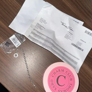 Thomas Sabo silver charms och armband - Säljer ett paket med Thomas Sabo Charm Club smycken: ett silverfärgat armband och tre olika berlocker – en ängel med texten 'Angel', en glittrig trollslända  och ett martiniglas med rosa detalj. Allt i äkta silver och levereras med originalaskar.