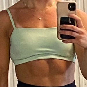 Mintgrön croppad topp från Gymshark - Säljer en mintgrön croppad topp från Gymshark med smala axelband och enkel, stilren design. Toppen är ärmlös och har en tight passform som passar perfekt till träning eller sommaroutfits. Mjuk och stretchig i materialet för maximal komfort.