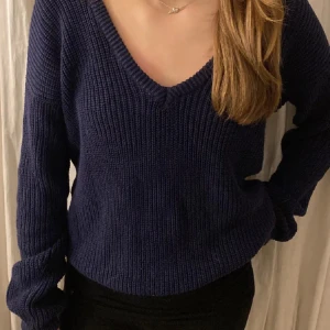 Mörkblå stickad v-ringad tröja NA-KD - Mysig mörkblå stickad tröja från NA-KD i storlek XS. Tröjan har en djup v-ringning, långärmade ärmar och en relaxed passform. Perfekt att slänga på sig när det är kyligt ute. Enkel och stilren design som funkar till det mesta. Nyskick