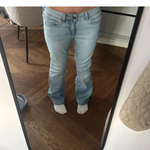 Ljusblå bootcut jeans från Hollister - Säljer ett par ljusblå bootcut jeans från Hollister, modell Curvy Mid-Rise Boot. Jeansen har klassisk femficksdesign, dragkedja och knapp framtill. Tillverkade i mjukt denimtyg som sitter snyggt och bekvämt. Perfekta för dig som gillar en avslappnad men trendig look.lågmidjade