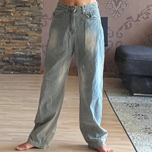 Baggy jeans från Lone Chaser  - Baggy jeans från Lone Chaser i ljusblå denim med slitna detaljer och bred passform. Hög midja och klassisk femficksdesign. Personen på bilden är ca 171 cm.