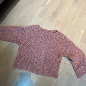 Rosa stickad tröja med loose fit - En mysig stickad tröja i melerad rosa ton med loose fit och långa ärmar. Tröjan har en enkel, avslappnad design och är lite croppad i modellen.