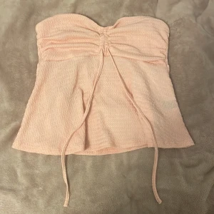 rosa tubtopp från shein - gullig rosa tubtopp från shein utan axelband, den har band så att man kan knyta antingen en rosett eller runt halsen om man föredrar det! säljer då den är för stor och aldrig kommer till användning💗💗skulle även säga att den har en annan nyans i verkligheten 