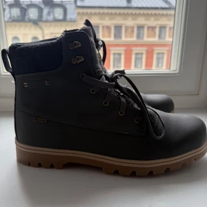 Gröna boots från McKinley strl 45 - Robusta gröna boots från McKinley med grov sula i brunt och svart. Skorna har snörning, vadderad krage och detaljer i syntetmaterial. Perfekta för kyligare dagar och outdoor-äventyr. Märkt med Aquamax och Ortholite för extra komfort.