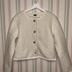 Vit teddyjacka från Gina Tricot L - Supermysig vit teddyjacka från Gina Tricot i storlek L. Jackan har rund halsringning, guldiga knappar framtill. Perfekt för dig som gillar en stilren och trendig look med lite extra fluff.