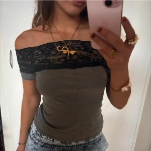 Grå offshoulder topp med spets - OBS! Öppen för prisförslag. Snygg grå offshoulder topp med svart spets upptill. Toppen är tight och har korta ärmar som sitter precis under axlarna. Spetsen ger en cool och feminin touch. Perfekt att matcha med jeans eller kjol för en trendig look.