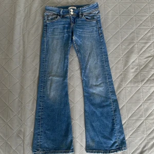 Blå bootcut jeans från Gina Tricot - Nypris: 400 kr – Säljes nu för endast 150!  Passa på att fynda dessa supersnygga Ginatricot low waist jeans i barnstorlek 140. Mörkblå med trendiga knappar istället för dragkedja – perfekt för den som vill ha stil och bekvämlighet till ett riktigt bra pris!                                                          