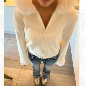 Vit stickad cardigan jacka med pälshuva - Helt oanvänd vit stickad cardigan jacka med fluffig pälskant på huvan. Jackan har dragkedja framtill, mysig & overzise känsla. Perfekt för kalla sommarkvällar / tidig höst! Bild 3 & 4 är inte mina bilder, det är från ett företag som säljer likadana jackor. Nypris: 1200 kr. 