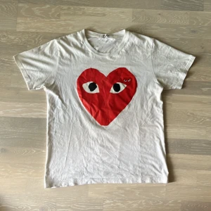 CDG t-shirt  - CDG PLAY T-shirt som är asfet! Liten skavank är att trycker att feadat lite men inget som stör (se bild 4). Storlek är 2XL men sitter som en L. Jag är 184 och den sitter bra på mig. Vid minsta fråga eller fundering hör av er🤝🏽