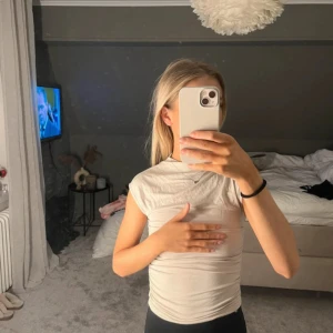 Beige ärmlös topp med rynkade sidor - Säljer en beige ärmlös topp med snygga rynkade detaljer längs sidorna. Toppen har en enkel, clean look med rund halsringning och är gjord i ett mjukt, stretchigt material som sitter skönt på kroppen. Perfekt att styla med jeans eller kjol.