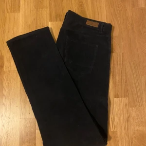 Svarta manchesterbyxor Massimo Dutti - Snygga svarta manchesterbyxor från Massimo Dutti med klassisk rak passform. Byxorna har diskreta bakfickor och är tillverkade i mjuk manchester som ger en stilren och tidlös look. Perfekta för dig som gillar en clean och enkel stil.