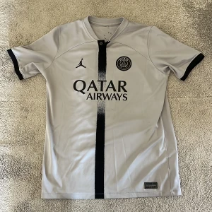PSG Neymar Jr fotbollströja Jordan  - Snygg PSG fotbollströja i vitt med svarta detaljer och tryck. Neymar Jr och nummer 10 på ryggen. Jordan-logga på bröstet och Paris Saint-Germain-märke. Kortärmad modell i lätt och ventilerande material, perfekt för match eller träning.priset kan deskuteras.