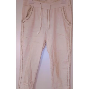 Beiga mjukisbyxor med snörning - Snygga vita trekvarts  mjukisbyxor med dragsko i midjan och dekorativa sömmar längs fickor och ben. Sköna och avslappnade, perfekta för chill dagar. Tillverkade i mjukt bomullsmaterial.