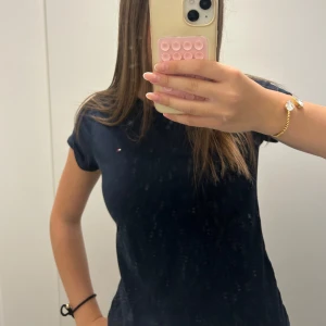 Mörkblå t-shirt från Tommy Hilfiger - Snygg mörkblå t-shirt från Tommy Hilfiger med liten broderad logga på bröstet. Klassisk passform och rund halsringning. Perfekt basic-plagg i mjuk bomull som funkar till allt.