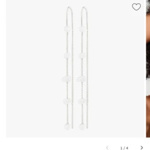 Långa örhängen med sötvattenspärlor - Superfina långa örhängen i silverfärgad metall med små vita sötvattenspärlor på en tunn kedja. De har en minimalistisk och elegant design som ger en clean look. Perfekta för dig som gillar stilrena smycken med en twist.