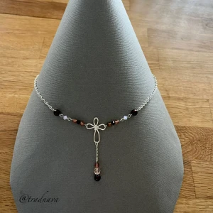”Kateri’s Kors” - Unikt handgjort korshalsband. Länkar och kedjor är i silverpläterad koppar och silverpläterad mässing, själva korset är i nontarnish-behandlad koppartråd från Wire Elements. Pärlorna går i ett brunt och rosa färgtema och är alla tjeckiska glaspärlor av olika slag; vaxade, firepolish och bicones (biconepärlorna är från Preciosa). Halsbandet har ett stavlås i försilvrad metall på baksidan. 