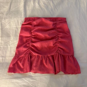 Rosa volangkjol från Gina Tricot - Supersöt rosa kortkjol från Gina Tricot med volangkant och rynkade detaljer framtill. Kjolen har en figurnära passform. 🫶🏼 Ge pris förslag