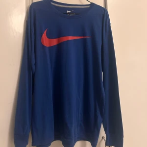 Blå långärmad Nike tröja - Blå långärmad tröja från Nike, det finns ingen logga där bak utan det är samma färg som tyget. Ett mjukt bomullsmaterial. Storleken är 2XL men sitter som en storlek L. 
