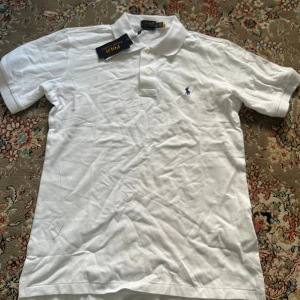 Vit pikétröja från Polo Ralph Lauren - Klassisk vit pikétröja från Polo Ralph Lauren i custom slim fit. Tröjan är i storlek s men funkar M med . Perfekt för en clean och stilren look.