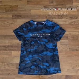 Tommy Hilfiger T-Shirt - Säljer en snygg Tommy Hilfiger T-shirt i storlek S, i nyskick.  Blått och svart camo-mönster med broderad Tommy Hilfiger-logga framtill (EST. 1985). Mjuk och bekväm bomullsblandning, normal passform. Perfekt för vardagsbruk och streetwear. Snabb leverans – skickas samma dag vid köp! Hör av dig vid frågor eller för fler bilder. 📦👕✨