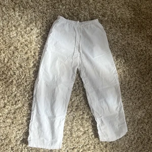 Vita linnebyxor från Gina Tricot - Snygga och luftiga vita linnebyxor från Gina Tricot med elastisk midja och snörning. Perfekta för varma dagar när du vill ha en chill och stilren look. Raka ben och enkel design som passar till allt.