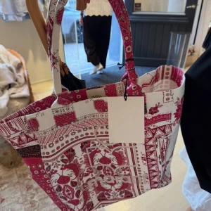 Isabel Marant väska - Stor shoppingväska från Isabel Marant i bomull med unikt röd- och vitmönstrat tryck. Väskan har två rejäla handtag och logotypen broderad framtill. Perfekt för att bära allt du behöver och sticker ut med sitt coola,  mönster.