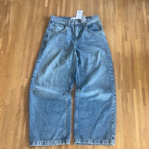 Blåa oversized jeans - Säljer ett par blågrå jeans i storleken 30/32. De är helt oanvända! Jeansen har en loose och wide passform med raka ben.