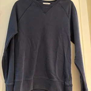 Mörkblå sweatshirt från WESC - En stilren mörkblå sweatshirt från WESC i klassisk modell. Tröjan har rund halsringning, långa ärmar och ribbade muddar vid ärmslut och nederkant. Perfekt för en chill och avslappnad look. Tillverkad i mjuk bomull för skön komfort.