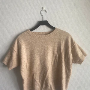 Beige stickad kortärmad tröja - Supermjuk beige stickad tröja med korta ärmar och rund hals. 