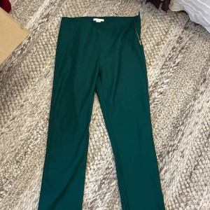 Mörkgröna byxor från H&M med dragkedja - Snygga mörkgröna byxor från H&M i storlek 38. Byxorna har en smal passform och stängs med en guldig dragkedja i sidan. 