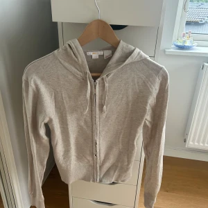 Beige hoodie med dragkedja Gina Tricot - Beige hoodie från Gina Tricot med dragkedja framtill och snörning i huvan. Tröjan har långärmade ärmar och ribbade muddar vid ärmslut och nederkant. Väldigt lik den från Soft Goat. Använd Max 2 gånger och inget som tyder på användning.💕💕
