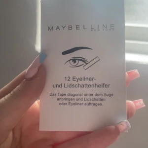 Maybelline eyeliner- och ögonskuggstape - 12-pack vita tejpremsor från Maybelline som hjälper dig få skarpa linjer när du applicerar eyeliner eller ögonskugga. Perfekt för att skapa en clean look och undvika sminkspill under ögonen. Enkel att använda och passar alla hudtoner.