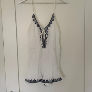 Jumpsuit - Kort vit jumpsuit med mörkblå detaljer. Vet ej märke och storlek, men gissar på XS.