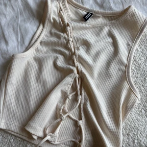 Vit topp med knytning Divided, Hm - Säljer en vit topp med knytning från Divided, Hm i storlek S. Den har inga större tecken på användning förutom en liten liten fläck på framsidan upptill halsen, något jag tror går att få bort.