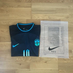 Brasilien Rodrygo #10 Nike fotbollströja S - Snygg mörkblå Brasilien fotbollströja från Nike med Rodrygo och nummer 10 på ryggen. Tröjan har korta ärmar, ljusblå detaljer och CBF-emblem på bröstet. Tillverkad i lätt och ventilerande material, perfekt för match eller träning.