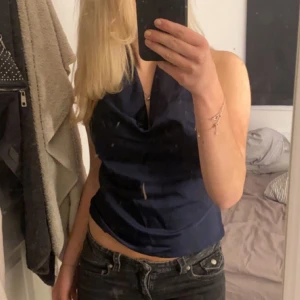 Mörkblå omlott linnetopp - Säljer en mörkblå omlott linnetopp med snygg draperad halsringning. Man knyter där bak i nacken så det blir en rosett