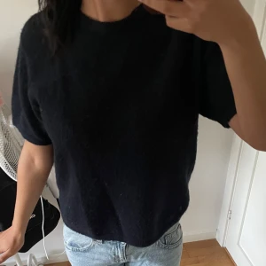 Mörkblå stickad kortärmad tröja - Säljer en mörkblå stickad tröja med korta ärmar. Tröjan har en enkel och clean design med rund hals och mjukt material som känns skönt mot huden. Perfekt att matcha med jeans eller kjol för en chill look.