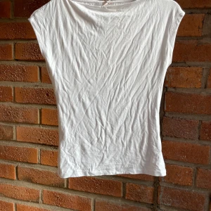 Vit ärmlös topp från Nelly - Enkel och stilren vit topp från Nelly i ärmlös modell. Toppen har rund halsringning och är gjord i mjuk bomull, perfekt för en clean och fräsch look. Passar till allt och är lätt att matcha med både jeans och kjol.