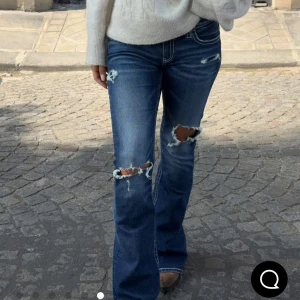 Mörkblå bootcut jeans med slitningar - Snygga mörkblå bootcut jeans med slitna detaljer och hål på knäna. Aldrig använda, storlek S, har fortfarande prislappen kvar! Har 36 