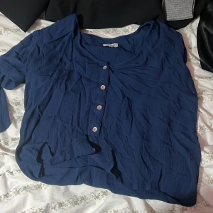 Blå blus med knappar från Bubbleroom - Säljer en snygg blå blus från Bubbleroom i storlek M. Blusen har ett krinklat tyg, rund halsringning och fyra silvriga knappar framtill. Långärmad och med en loose passform som ger en chill vibe. Perfekt att styla med jeans eller kjol.