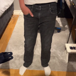 Svarta Replay jeans straight fit - Säljer ett par svarta jeans från Replay i straight fit. Jeansen har normal midja och är tillverkade i bomull. Snyggt tvättade med en mörk ton och diskreta slitningar för en cool look. 