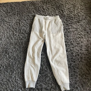 Grå mjukisbyxor Polo Ralph Lauren XL - Snygga ljusgrå mjukisbyxor från Polo Ralph Lauren med breda muddar, stora fickor framtill och dragsko i midjan. Sköna och avslappnade, perfekta för chill dagar. Tillverkade i mjukt bomullsmaterial.