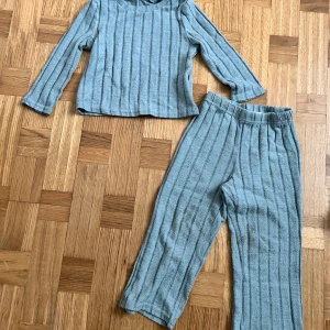 Grå ribbad långärmad tröja barn - Mysig grå långärmad tröja med ribbad struktur och rund hals. Perfekt för chill dagar hemma eller när du vill ha något skönt på dig. Materialet känns mjukt och har en snygg randig look. Passar barn i åldern 3-4 år.