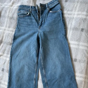 Blå raka jeans från H&M, strl 36 - Klassiska blå jeans från H&M i rak modell med normal passform. Jeansen har fem fickor, bälteshällor och snygga kontrastsömmar. Perfekta till sneakers eller boots och funkar året runt.