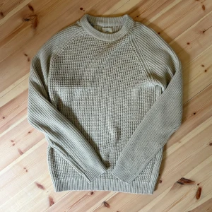 Beige stickad tröja från Selected Homme - Säljer en beige stickad tröja från Selected Homme. Tröjan har grovstickad struktur, rund halsringning och långa ärmar. Perfekt för lager-på-lager och chill stil. Passar dig som gillar klassiska och stilrena plagg.
