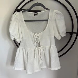 Vit blus med puffärm och knyt - Supersöt vit blus från Gina Tricot med puffiga korta ärmar och två knyt framtill. 