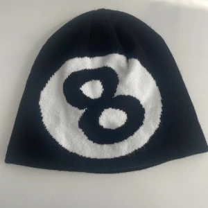 Svart mössa med åtta-boll motiv - Cool svart mössa med stort åtta-boll motiv i vitt och svart framtill. 