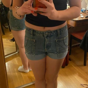 Blå jeansshorts med coola detaljer - Ett par blå jeansshorts  som är snygga, har unika fickor fram och bak. Säljer då de är för små för mig!